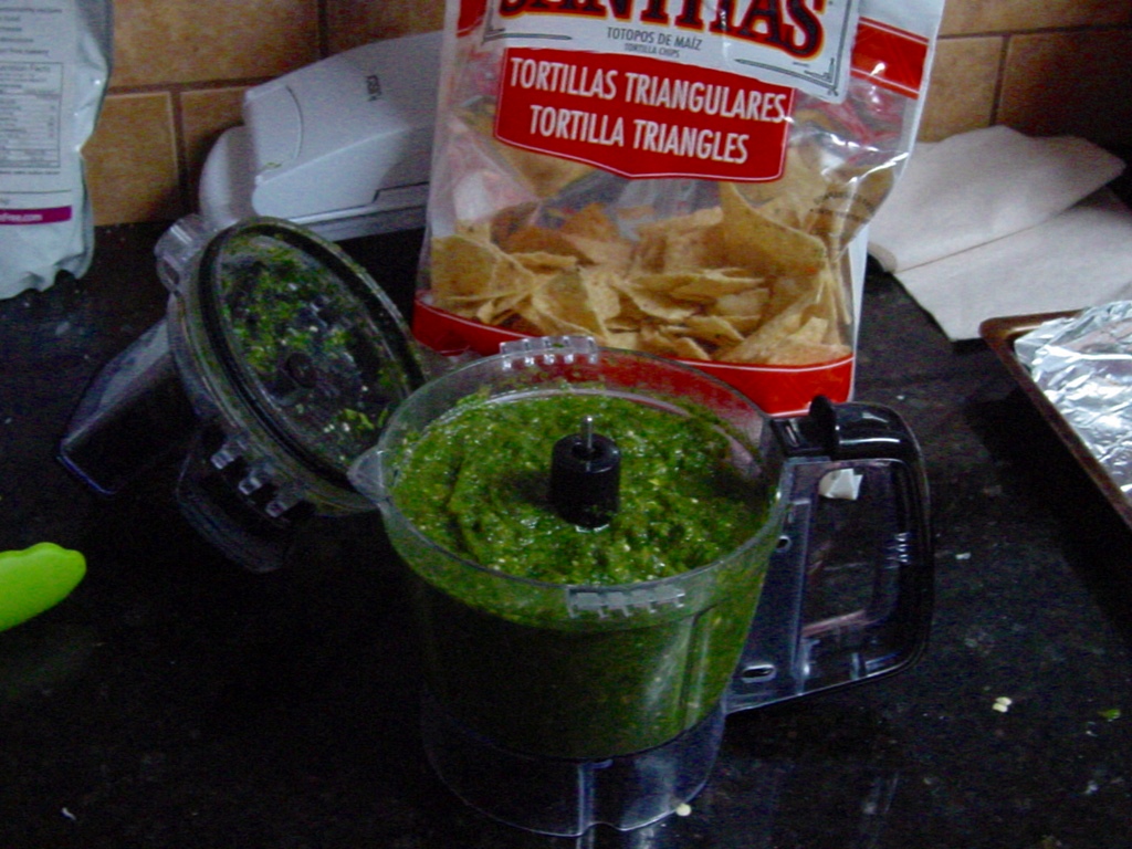 Salsa in a food processor, with tortilla chips
 in the background.